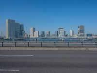 the highway and bridge leading to a city in japan and has tall buildings and blue skies