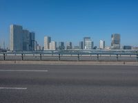 the highway and bridge leading to a city in japan and has tall buildings and blue skies