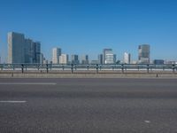 the highway and bridge leading to a city in japan and has tall buildings and blue skies