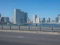 the highway and bridge leading to a city in japan and has tall buildings and blue skies