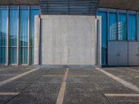 a sidewalk that has several glass doors next to it with buildings in the background behind