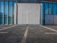 a sidewalk that has several glass doors next to it with buildings in the background behind