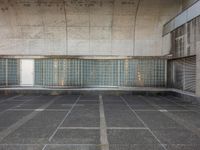 two empty parking spaces with two empty doors and a large window on the wall between two buildings