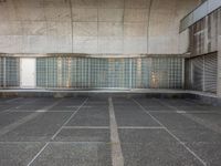 two empty parking spaces with two empty doors and a large window on the wall between two buildings