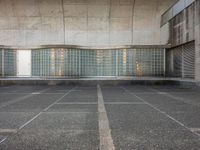 two empty parking spaces with two empty doors and a large window on the wall between two buildings