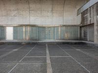 two empty parking spaces with two empty doors and a large window on the wall between two buildings