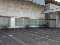 two empty parking spaces with two empty doors and a large window on the wall between two buildings