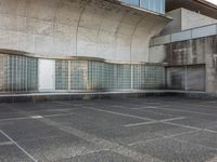 two empty parking spaces with two empty doors and a large window on the wall between two buildings