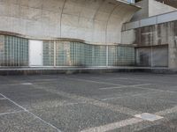 two empty parking spaces with two empty doors and a large window on the wall between two buildings