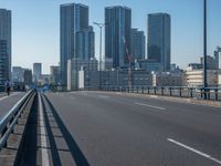 the highway and bridge leading to a city in japan and has tall buildings and blue skies