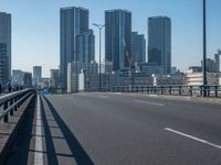 the highway and bridge leading to a city in japan and has tall buildings and blue skies