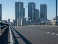 the highway and bridge leading to a city in japan and has tall buildings and blue skies