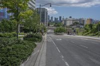 a road with buildings in the background on a bright day with clouds in the sky