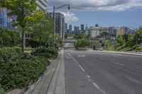 a road with buildings in the background on a bright day with clouds in the sky