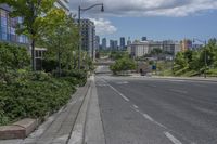 a road with buildings in the background on a bright day with clouds in the sky