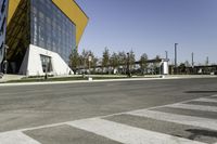 a man riding his bike down the road on a sunny day with a large building in the background