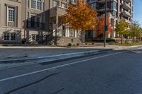 a street intersection with parking spaces and a stop sign, the sidewalk is empty, and one of the sides is empty