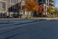 a street intersection with parking spaces and a stop sign, the sidewalk is empty, and one of the sides is empty