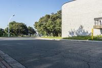 this is an empty street and one car going by it and a building in the background