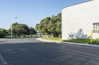 this is an empty street and one car going by it and a building in the background