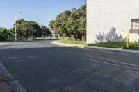 this is an empty street and one car going by it and a building in the background