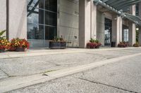 a parking meter that is sitting on the sidewalk of a building, with potted plants