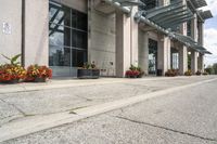 a parking meter that is sitting on the sidewalk of a building, with potted plants