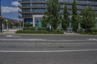 a building with two tall trees in front of it on a street corner with buildings behind