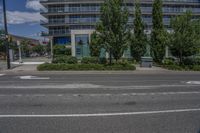 a building with two tall trees in front of it on a street corner with buildings behind