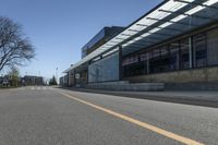 the empty road is lined with empty trees in the front of this building at the end of the street