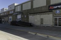 a guy on skateboard in front of a brick building by a parking garage and some stairs