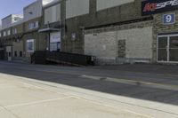 a guy on skateboard in front of a brick building by a parking garage and some stairs