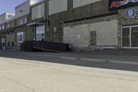 a guy on skateboard in front of a brick building by a parking garage and some stairs