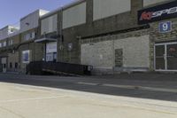 a guy on skateboard in front of a brick building by a parking garage and some stairs