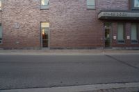 a very red brick building with an entrance way that goes down the front street to the sidewalk