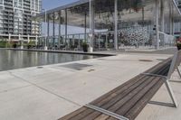 a row of wooden benches overlook a water feature on the left side of the walkway