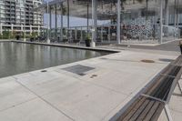 a row of wooden benches overlook a water feature on the left side of the walkway