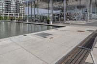 a row of wooden benches overlook a water feature on the left side of the walkway