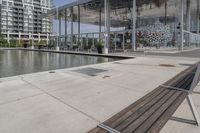 a row of wooden benches overlook a water feature on the left side of the walkway