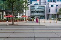 a woman in a pink dress standing on a city street corner holding a cell phone