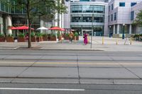 a woman in a pink dress standing on a city street corner holding a cell phone