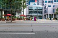 a woman in a pink dress standing on a city street corner holding a cell phone