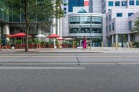 a woman in a pink dress standing on a city street corner holding a cell phone