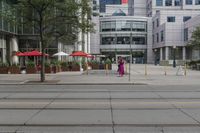 a woman in a pink dress standing on a city street corner holding a cell phone