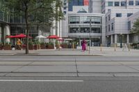 a woman in a pink dress standing on a city street corner holding a cell phone