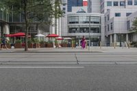 a woman in a pink dress standing on a city street corner holding a cell phone