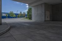 an empty paved sidewalk with building in the background and park in front of it on a sunny day