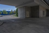 an empty paved sidewalk with building in the background and park in front of it on a sunny day