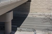 a bridge over a street that has a bench in the middle of it and a sidewalk underneath it