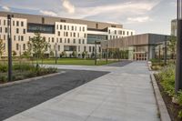 the walkway has white benches in front of it to the side of a building with several windows